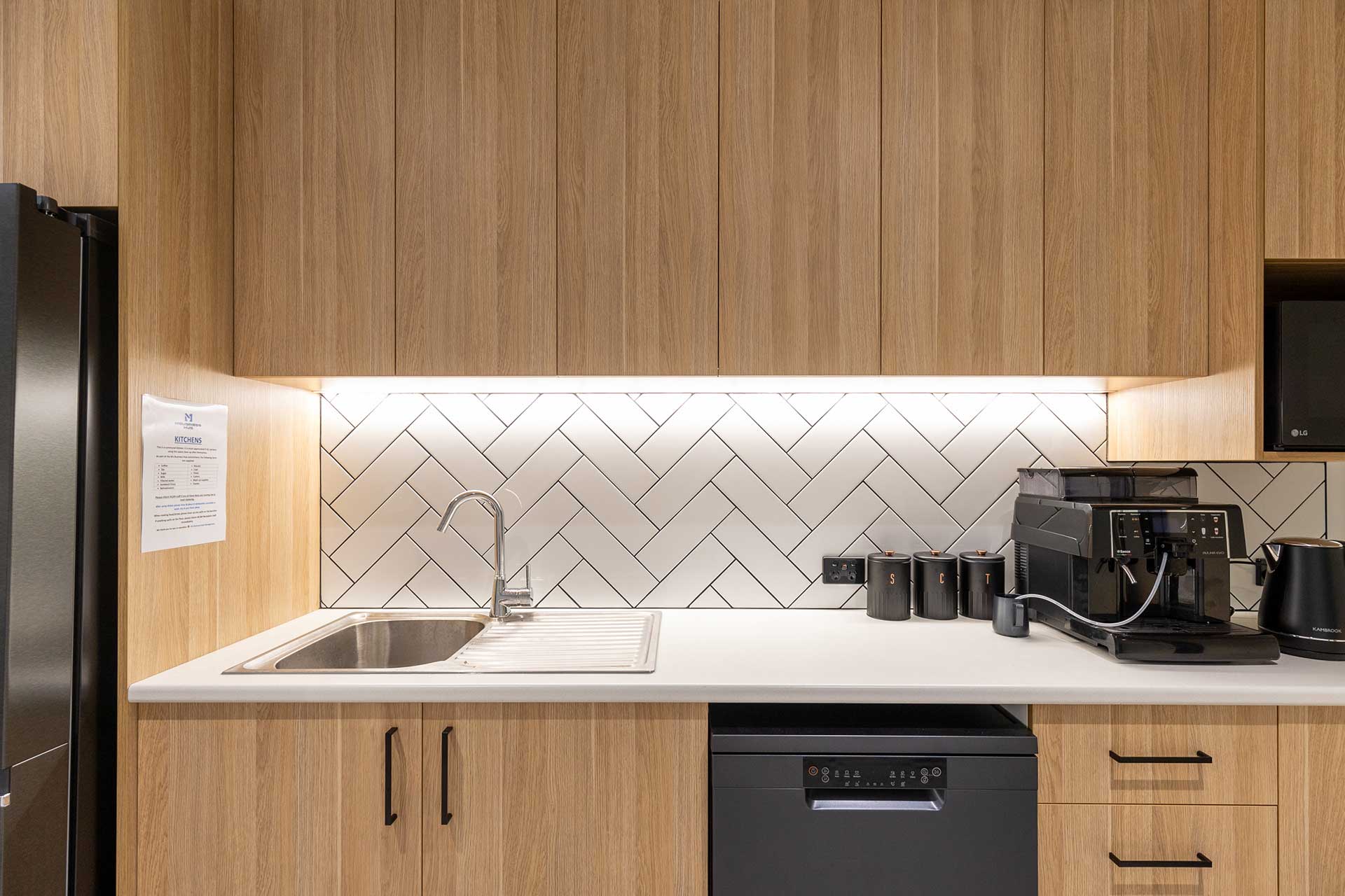 Modern office kitchen with herringbone tile backsplash by Airey Building Group.